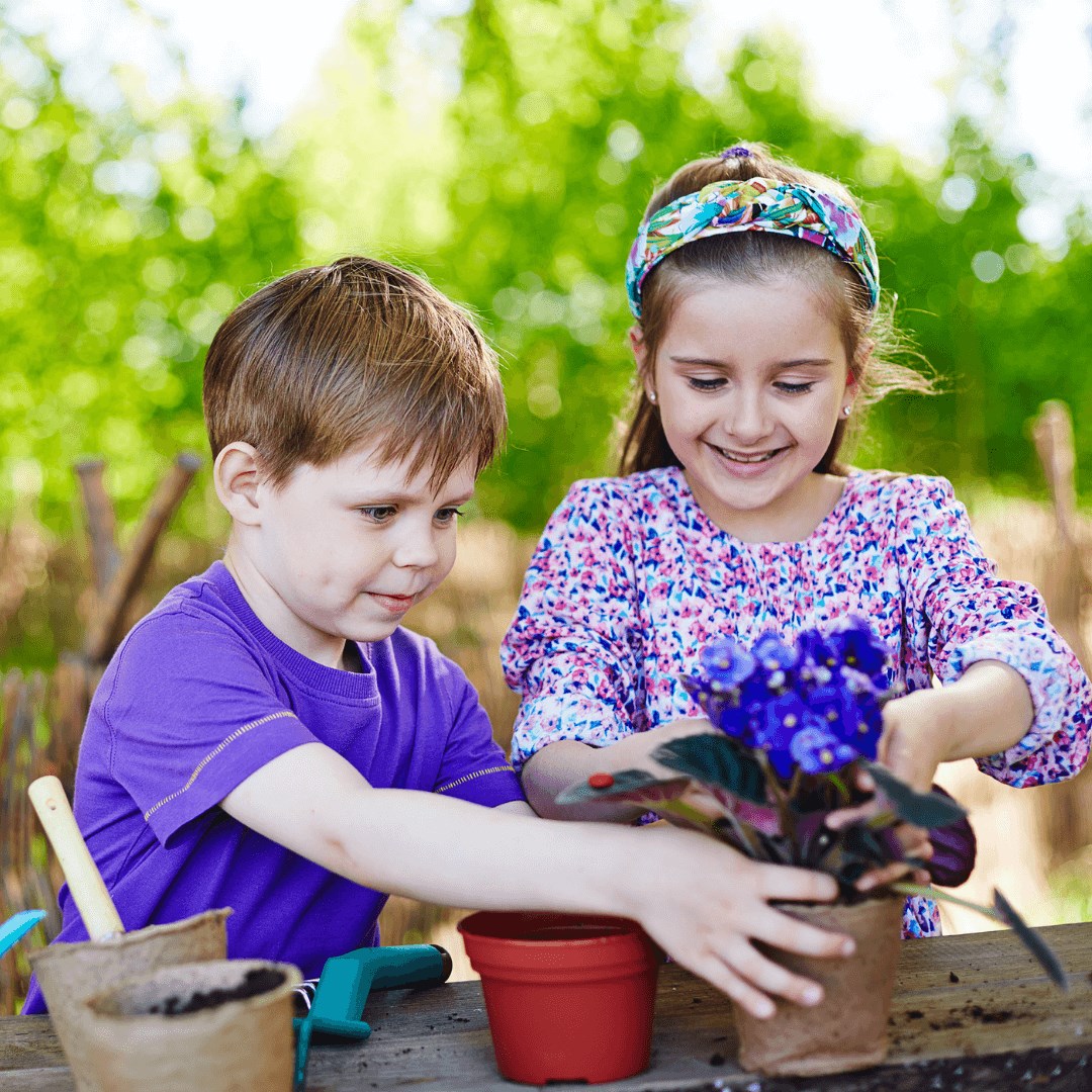 Two kids potting a flower on a garden table