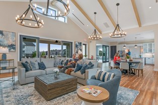 Residents relaxing and socializing inside the stylish community clubhouse in Stafford, VA, featuring cozy seating, modern chandeliers, and an open-concept kitchen at Embrey Mill.